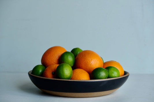 A large serving dish that's dipped in black satin glaze with a raw rim and raw foot, handmade from speckled stoneware.